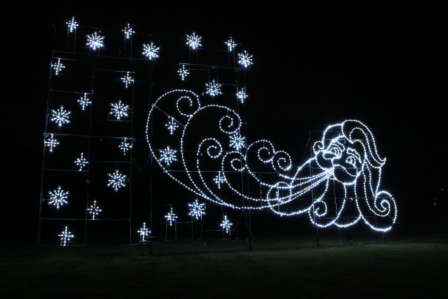 Illuminated winter mural with stars and a figure blowing wind at night.