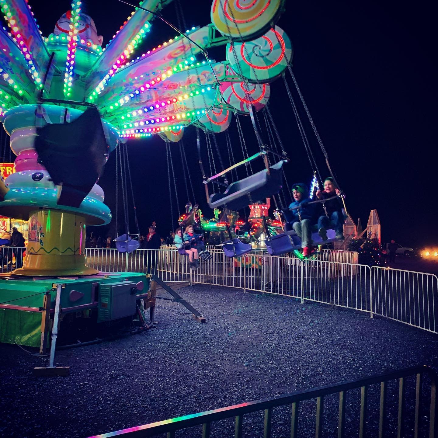 Colorful carousel swing ride at night, people enjoying the ride.