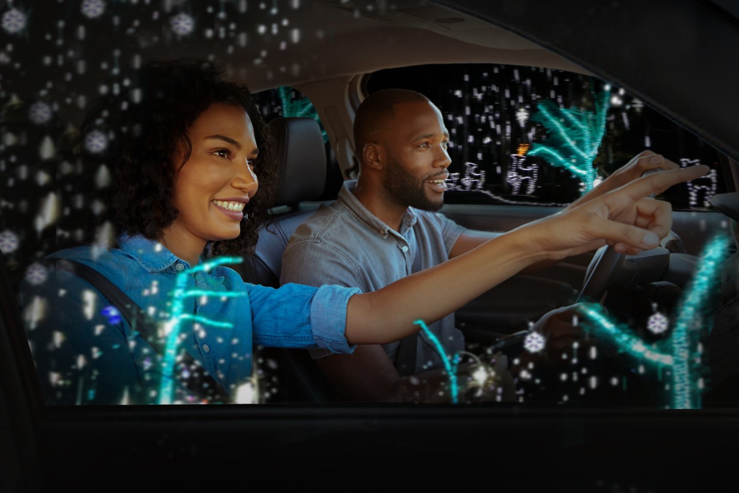 A woman points excitedly while a man drives through a twinkling light display at night.