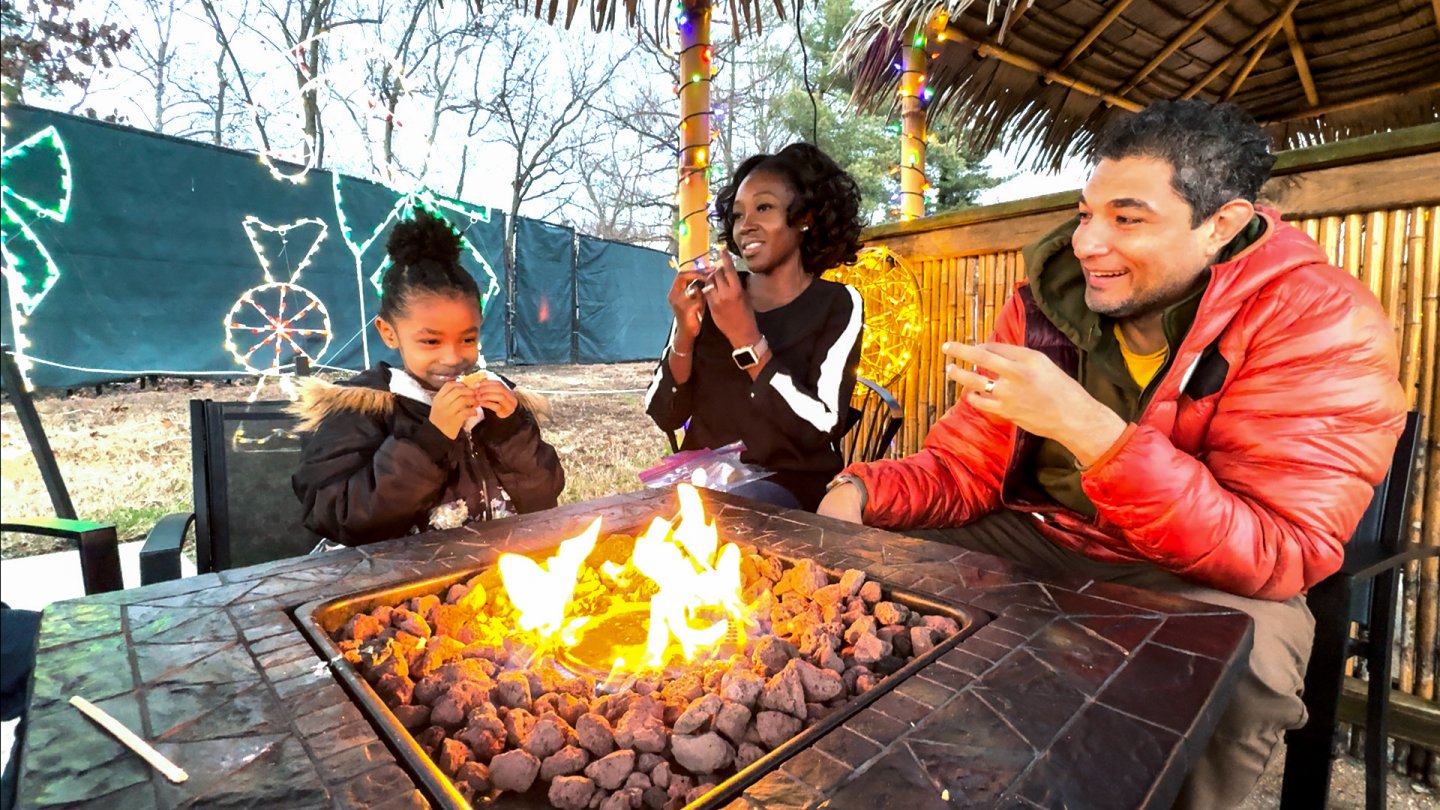 Family enjoying a fire pit in a festive outdoor setting.